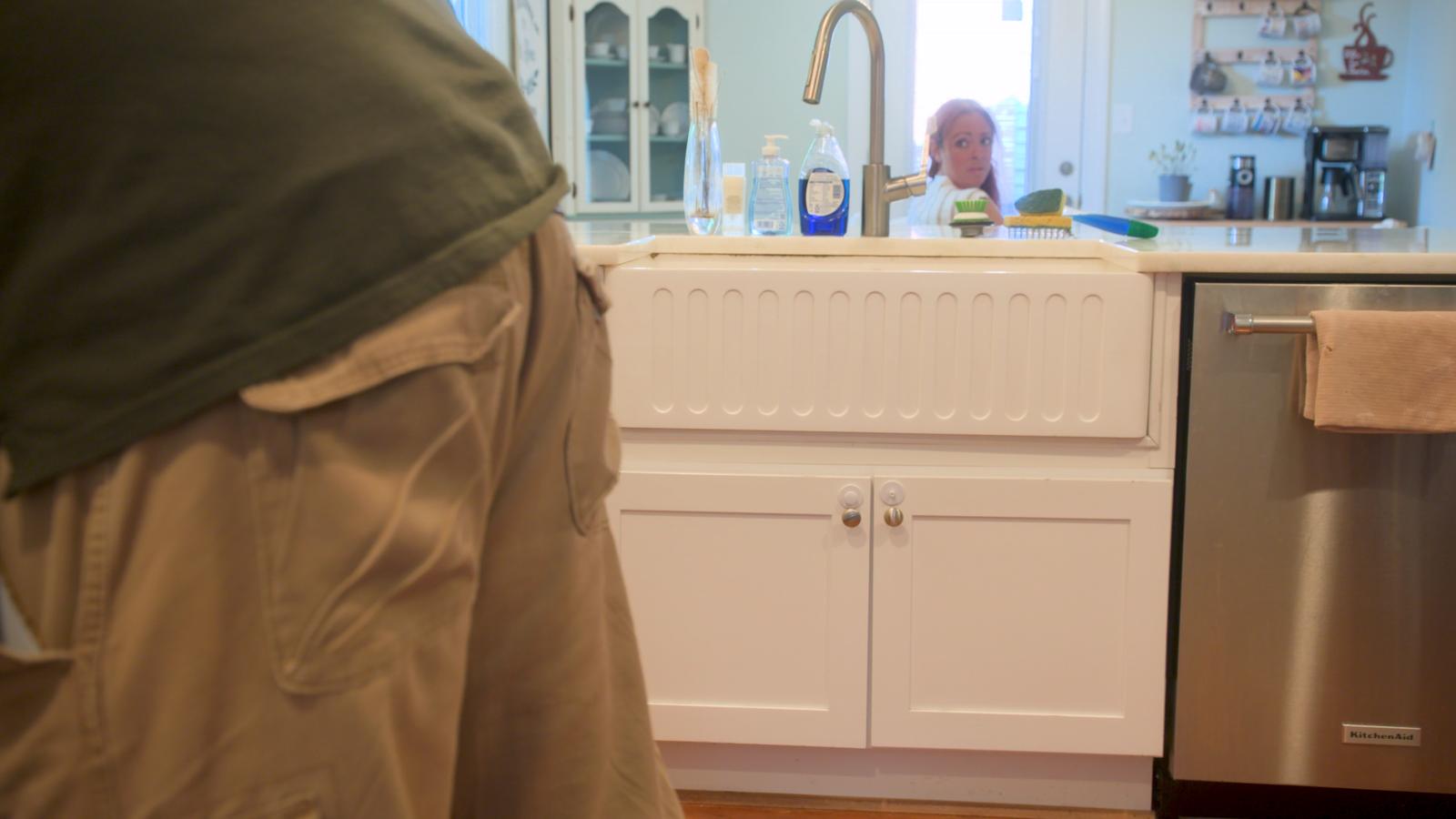 Joanne peers over the kitchen sink