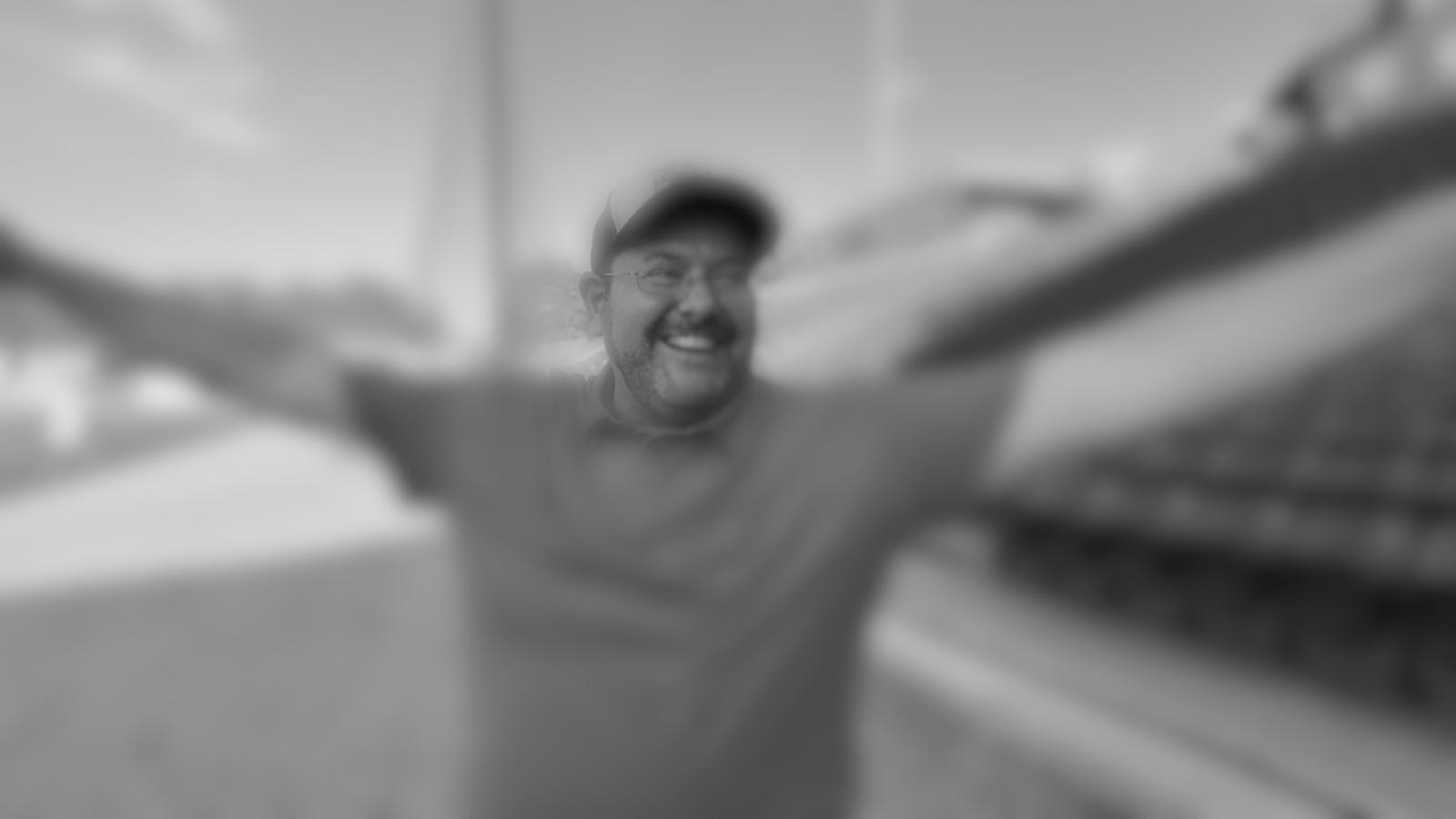 Brad, arms wide, grinning at a ballfield
