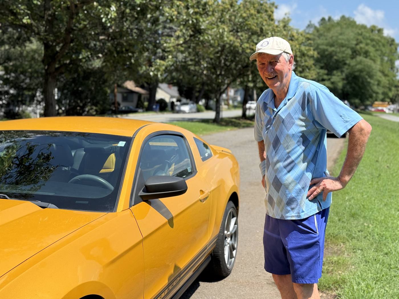 Wayne grins beside his yellow Mustang